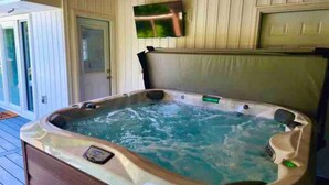 A hot tub with a control panel, a television mounted above it, and a door leading to a covered deck. - GOTL - Hot Tub - Wine Tours - Sunset Vacation Rentals (Geneva)