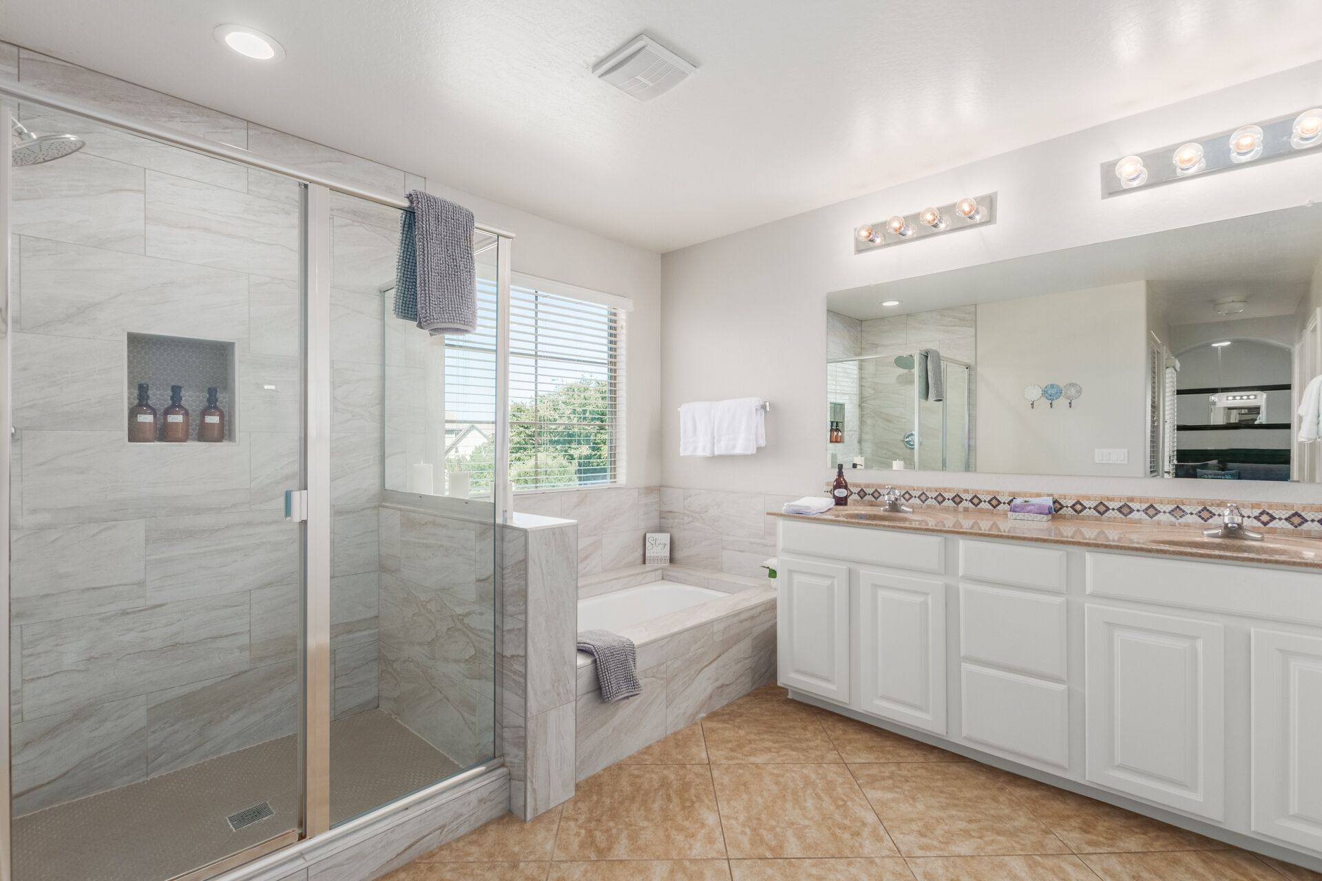 Une salle de bain moderne dotée d’une douche à parois de verre, d’une baignoire et d’un meuble-lavabo avec un grand miroir.