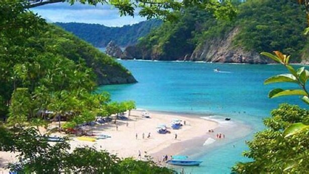 A beach with clear turquoise water, surrounded by lush greenery and rocky cliffs. - Paradise Found!  Spacious Tropical Private Retreat! (Jaco)