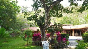 A garden with a stone pathway leading to a building with a tiled roof. - Paradise Found!  Spacious Tropical Private Retreat! (Jaco)