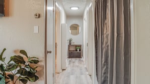 A hallway with a wooden floor, a mirror on the wall, and a plant on the left. - This house is a 2 bedroom(s), 1 bathrooms, located in Abilene, TX. (Abilene)