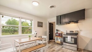 A kitchen with a wooden table, white chairs, a microwave, and an oven. - Cut the claustrophobia in hotels, enjoy freedom and quality space. (Abilene)