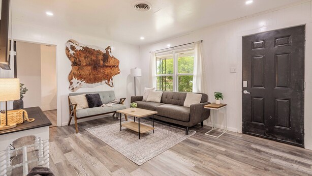 A modern living room with a large wall mural, a grey sofa, a wooden coffee table, and a black door. - Cut the claustrophobia in hotels, enjoy freedom and quality space. (Abilene)