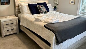 Une chambre à coucher avec un lit, des tables de chevet, un ventilateur de plafond et des tableaux encadrés accrochés au mur.