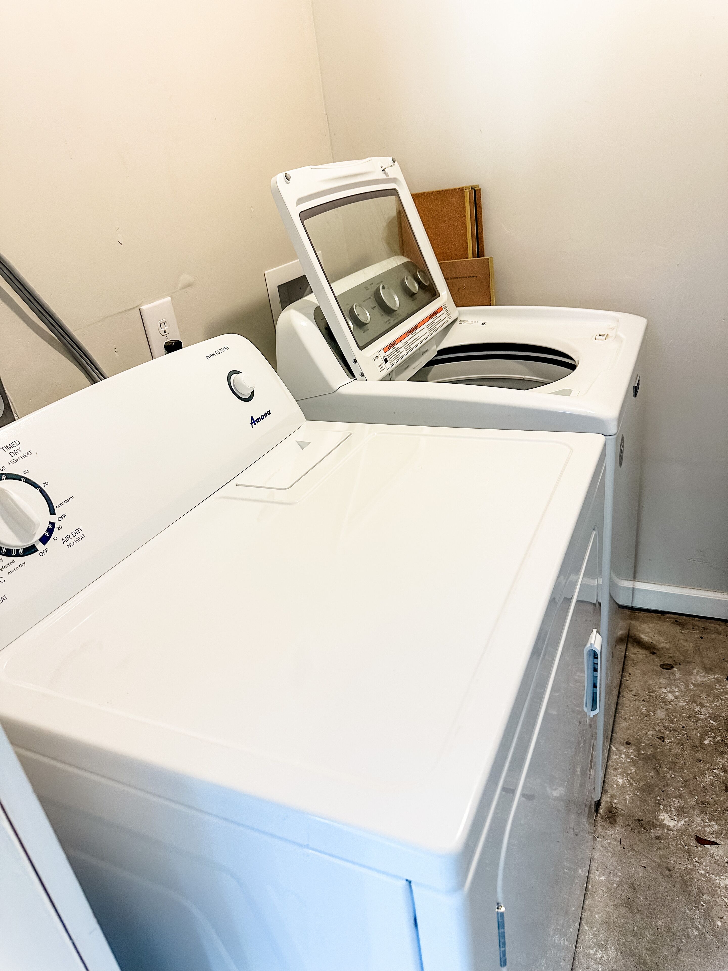 Un espace buanderie équipé d’un lave-linge et d’un sèche-linge à chargement frontal, d’un panneau de commande avec différents réglages et d’une prise de courant.