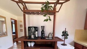 A kitchen with a wooden coffee station, a refrigerator, and a hanging plant. - The Gemini (Elkhart)