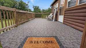 A wooden deck with a welcome mat, a chair, and a 'welcome' sign.