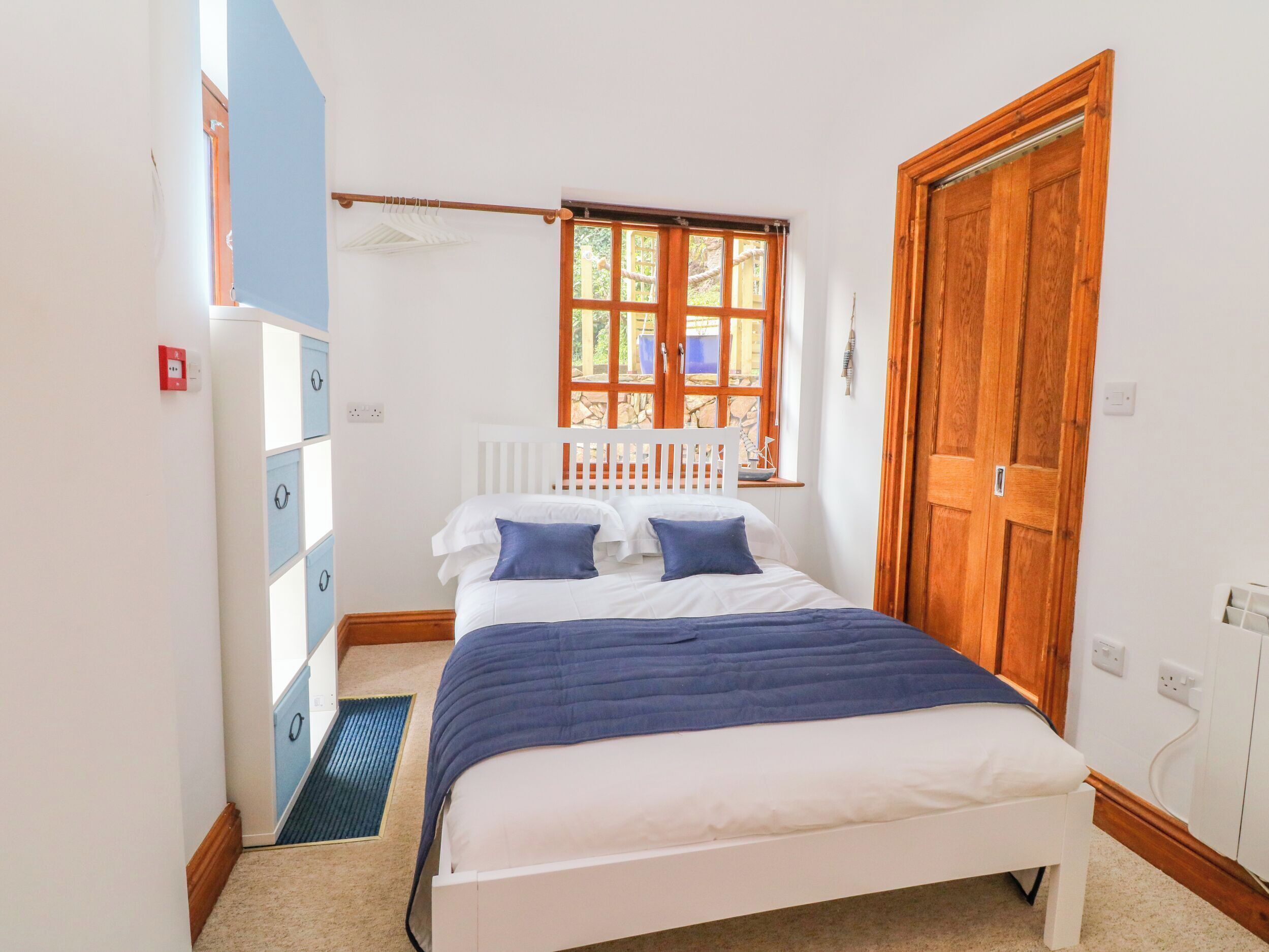A bedroom with a bed, a window, a wardrobe, and a door.