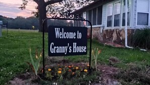 Une pancarte accueillante indiquant « Chez grand-mère », avec une maison en arrière-plan.