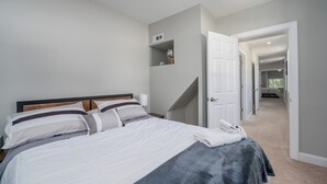 Une chambre à coucher comprenant un lit, une table de chevet, une étagère avec des objets décoratifs et une porte donnant sur une autre pièce.