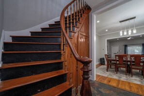 Un escalier en bois au design incurvé mène à un espace repas comprenant une table et des chaises.