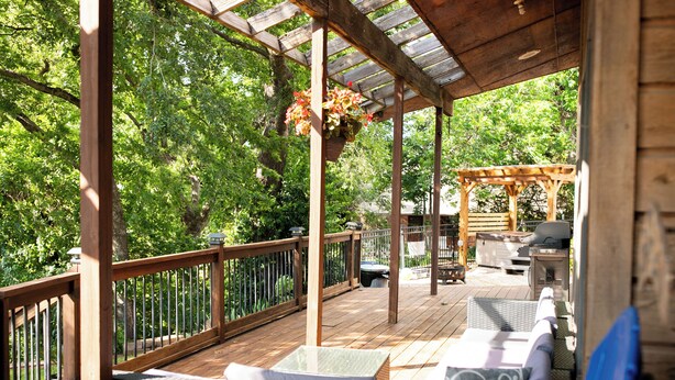 A covered outdoor deck with wicker furniture, a hanging flower basket, and a wooden pergola. - Lake Oasis w/Pool, Hot tub, Gym (Warr Acres)