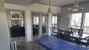 A modern kitchen with blue tiles, a dining area with wooden chairs, and a view of the outdoors. - Lake Oasis w/Pool, Hot tub, Gym (Warr Acres)