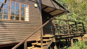 A wooden cabin with a staircase leading to a deck. - Buhleni Farm & Chalets (Lobamba)