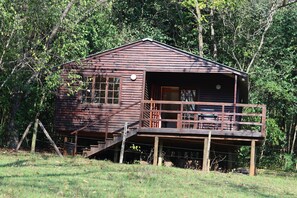 A wooden cabin with a balcony, surrounded by trees. - Buhleni Farm & Chalets (Lobamba)