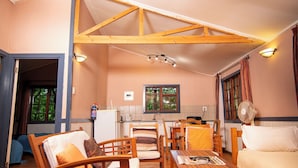A cozy room with wooden furniture, a dining area, and a kitchen. - Buhleni Farm & Chalets (Lobamba)