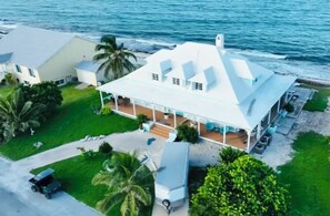 Ein Küstenhaus mit einer großen Veranda, einer überdachten Sitzgelegenheit im Freien und Blick aufs Meer.