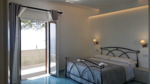 A bedroom with a bed, a nightstand, a wall-mounted lamp, and a sliding glass door leading to an outdoor area.