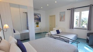 A modern hotel room with a large bed, a sitting area, a shower, and a view of the outdoors.