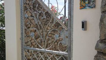 A metal gate with decorative patterns, a stone wall, and a sign that reads "Villa Auroris apartment".