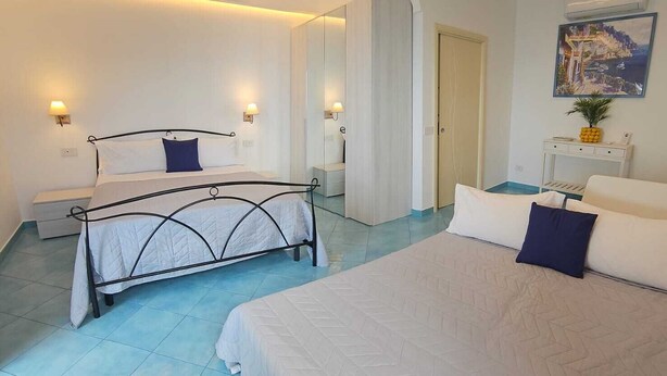 A modern hotel room with two beds, a large mirror, a painting, and a small table with a pineapple. - Villa Furoris Apartment, welcome to home! (Furore)