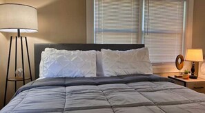 Cozy retreat with a large bed, bedside table, and potted plant.