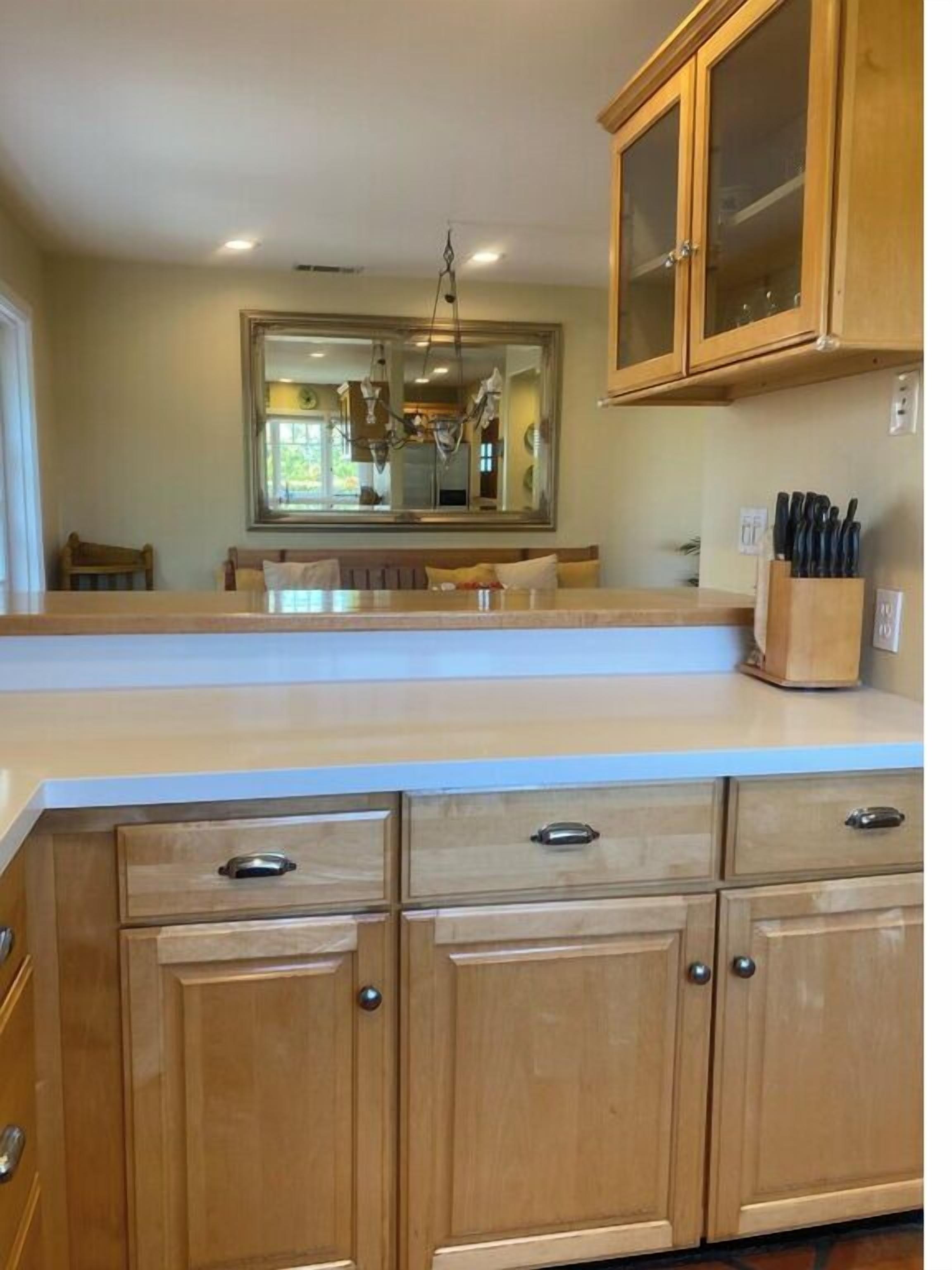 A kitchen with wooden cabinets, a white countertop, and a hanging light fixture.