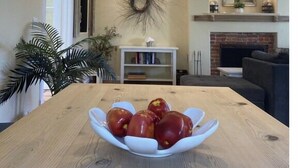 A dining area with a wooden table, a bowl of tomatoes, a chandelier, a fireplace, and a mirror on the wall. - FUN at the beach and park with Family & Friends! (Santa Barbara)