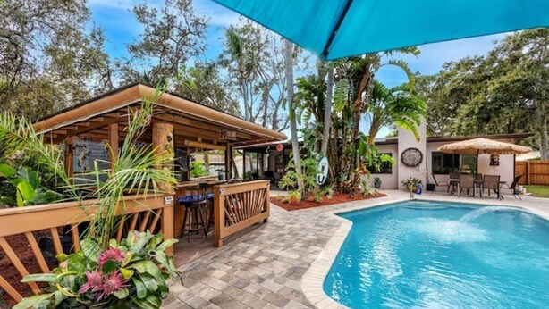A poolside area with a bar, seating, and a covered patio. - Paradise in Clearwater (Clearwater)