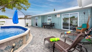 Un jardin avec une piscine, des meubles de patio et un espace salon abrité.