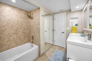 Une salle de bain avec une baignoire, une douche, un lavabo et un miroir.