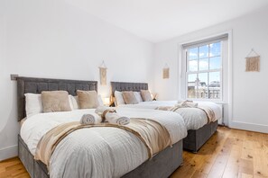 Une chambre moderne avec deux lits, une grande fenêtre et une vue sur la ville.