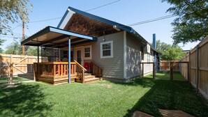 Une maison de plain-pied avec un porche couvert, une cour clôturée et une terrasse en bois.