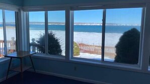 A room with large windows offering a view of the sea and a snowy landscape.