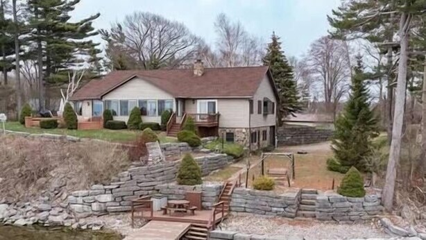 A house with a stone retaining wall and a dock extending into a pond.