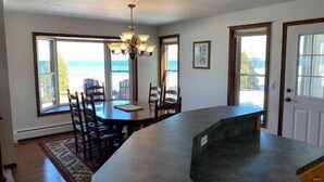 A kitchen with a large island, dining table, chairs, and a view of the ocean.