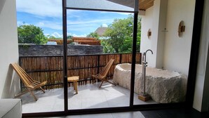 A balcony with two wooden chairs, a small table, and a stone water feature. - Jungle Retreat with Private Tub & Cenote (Tulum)