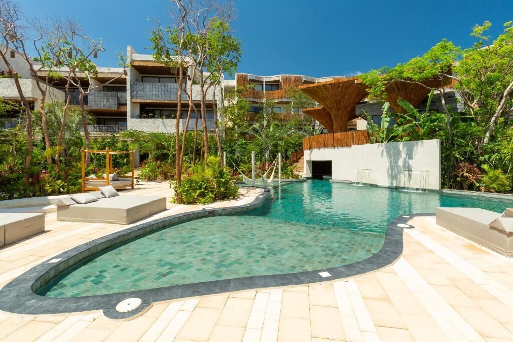 Une piscine au design incurvé, entourée d’espaces de détente en plein air et de verdure.