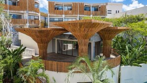 A modern building with a unique architectural design featuring wooden slats and a central open space. - Jungle Retreat with Private Tub & Cenote (Tulum)