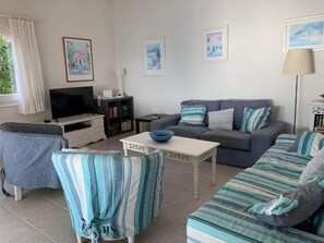 A living room with a sofa, armchairs, a television, and a coffee table.