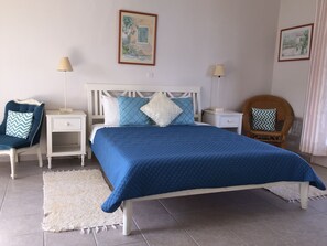 A bedroom with a bed, two bedside tables, a chair, and two lamps.