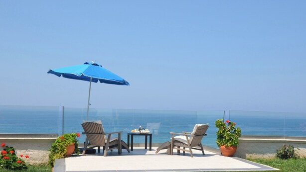 A terrace with two chairs, a table, and a blue umbrella overlooking the sea. - WATERFRONT VILLA SEAHORSE BAY- HALIKOUNAS (Chalikounas)