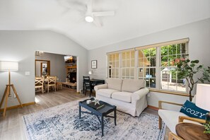 A living room with a sofa, coffee table, and a large window with shutters.