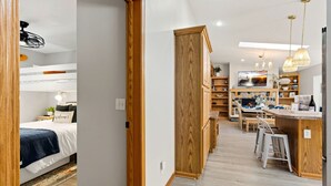 Un intérieur moderne comprenant un lit superposé, des meubles en bois, un coin cuisine et un espace repas.