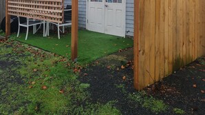 Une maison avec une porte blanche, deux guirlandes, une clôture en bois et une pergola.