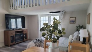 A cozy living room with a wooden dining table, a TV, a sofa, and a plant. - Saltline Studio
 (Tillamook)