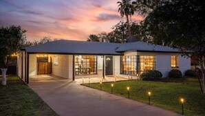 Una casa moderna con un porche cubierto, ventanas amplias y un camino de entrada bien iluminado.