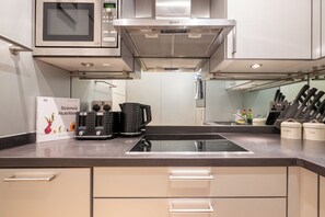 A modern kitchen with a microwave, stove, and various appliances. - Newly Renovated 1BDR in Knightsbridge with WiFi (London)