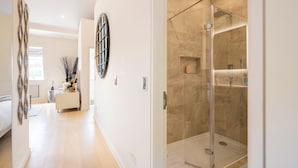 A modern bathroom with a glass-enclosed shower, a vanity with a mirror, and a light-colored tiled floor. - Newly Renovated 1BDR in Knightsbridge with WiFi (London)