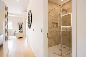 A modern bathroom with a glass-enclosed shower, a vanity with a mirror, and a light-colored tiled floor. - Newly Renovated 1BDR in Knightsbridge with WiFi (London)